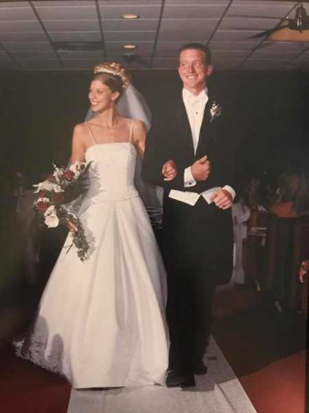 Young couple walk down the aisle together at their wedding reception