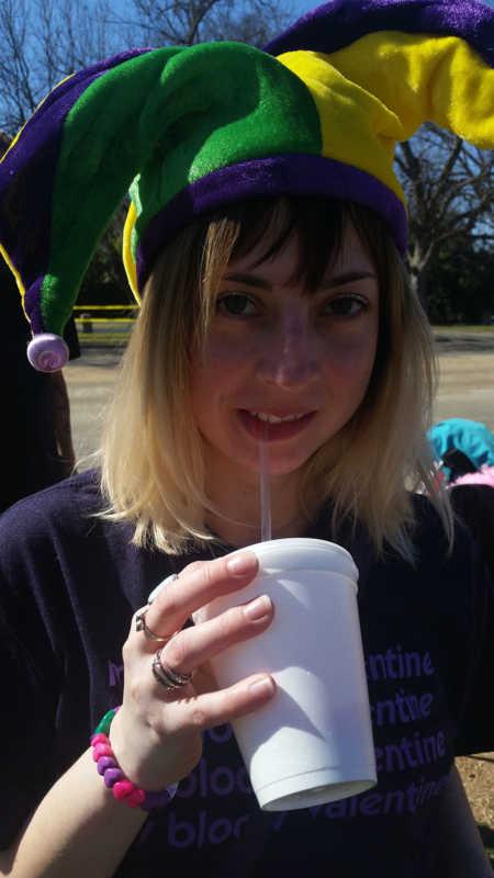 Woman enjoys an alcoholic beverage while celebrating Mardi Gras