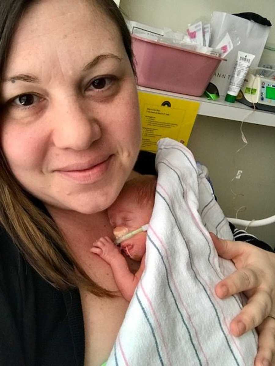 Mom looks tired while holding newborn baby in the hospital