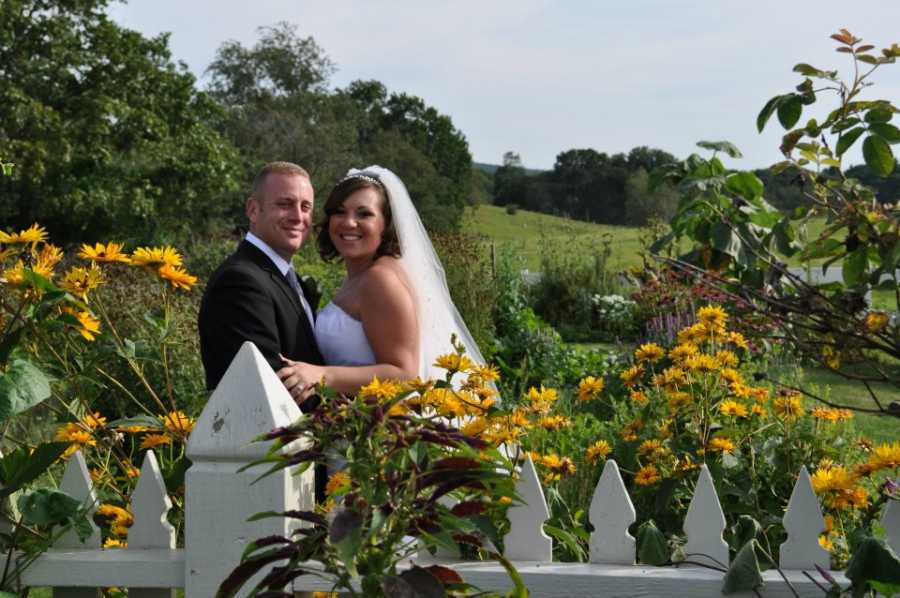 Couple take photos in a field of sunflowers on their wedding day