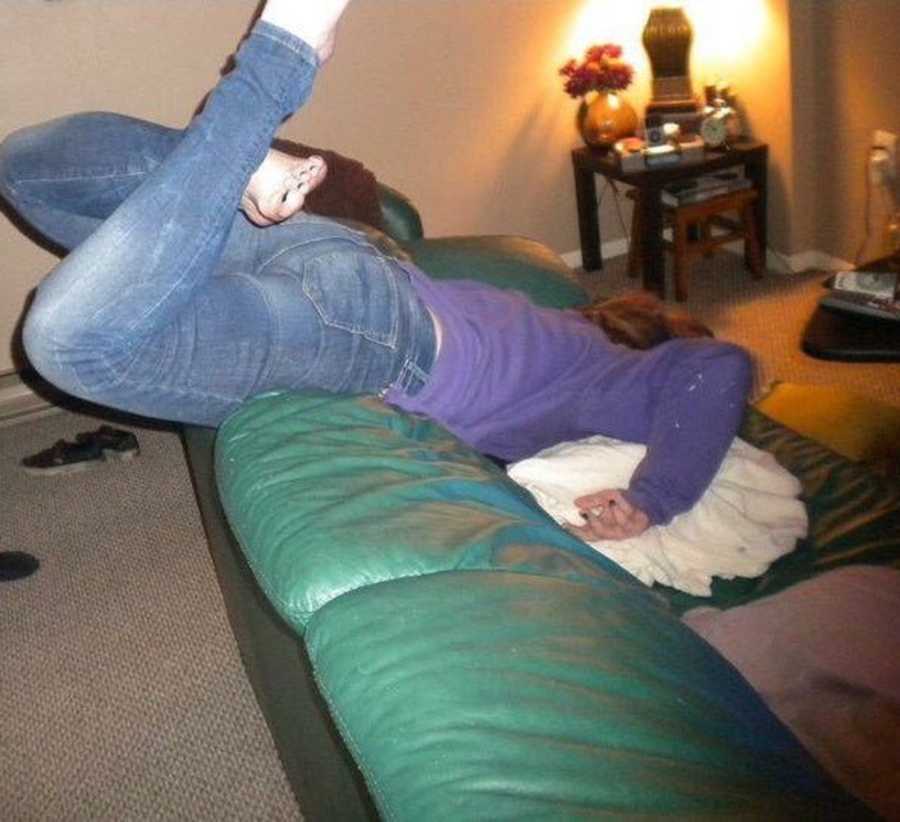 Young woman battling alcoholism sleeps facedown on a green couch after a night of drinking