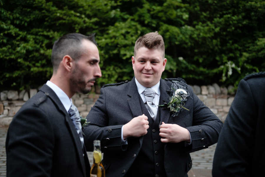 Groom takes candid photo with one of his groomsmen before wedding ceremony