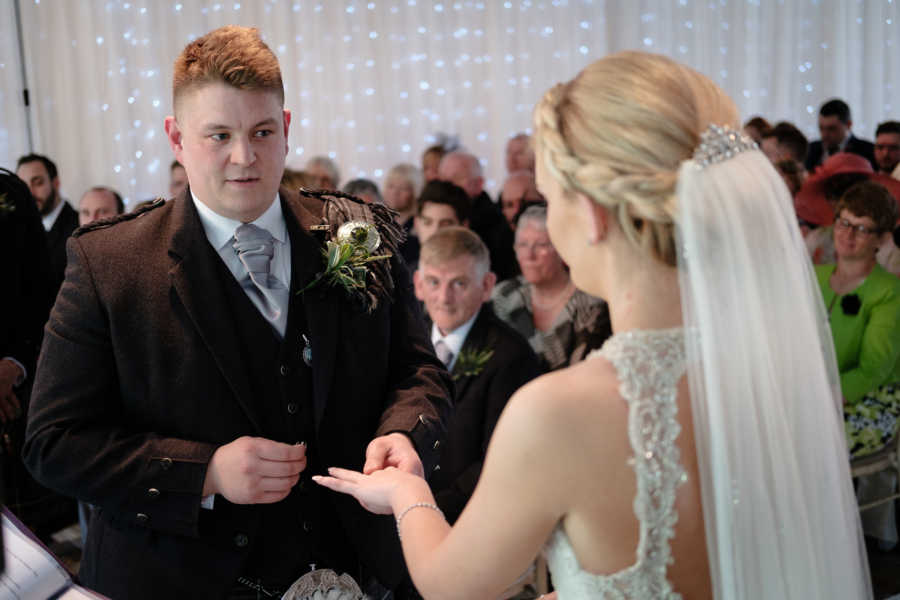 Man puts wedding ring on his wife during wedding ceremony