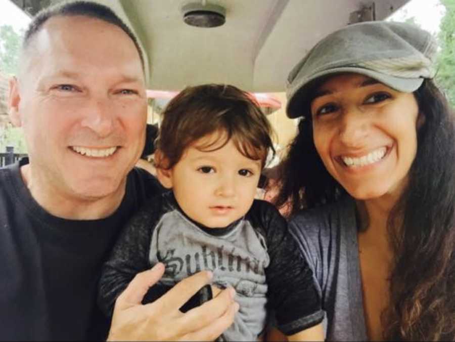 Older parents take a selfie with their young son while riding in a golf cart 