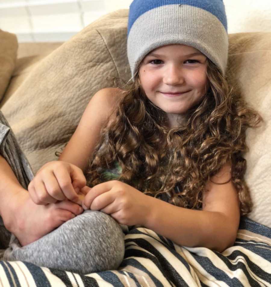 mom takes photo of daughter chilling on the couch with long curly hair and a beanie on