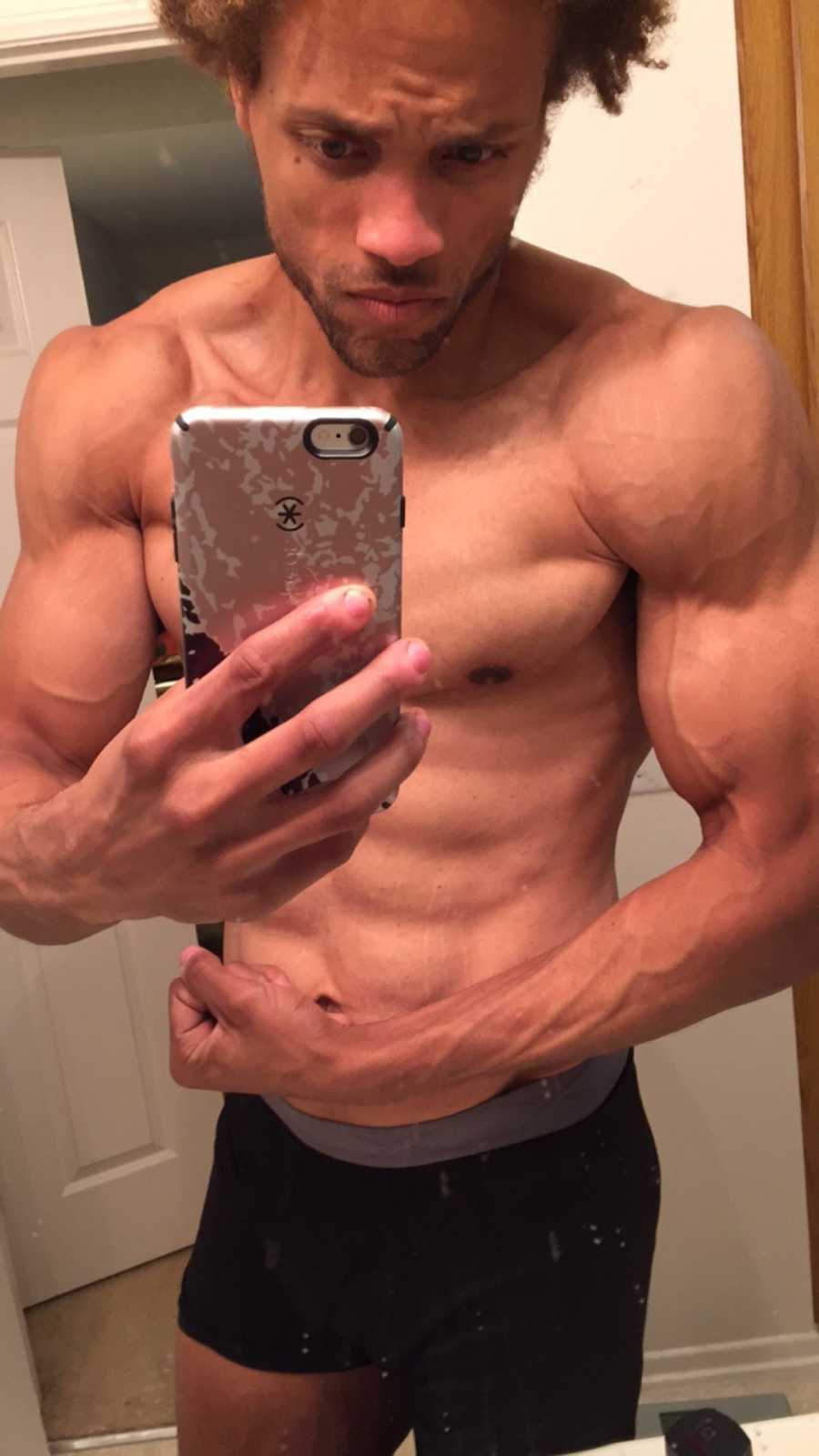 Man takes a shirtless mirror selfie while flexing his biceps