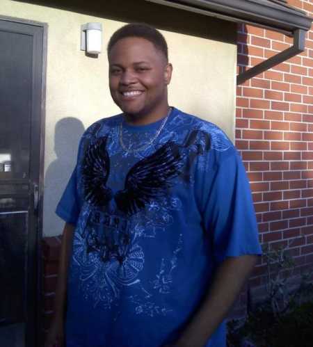 Man poses for a photo in a blue shirt with wings on it