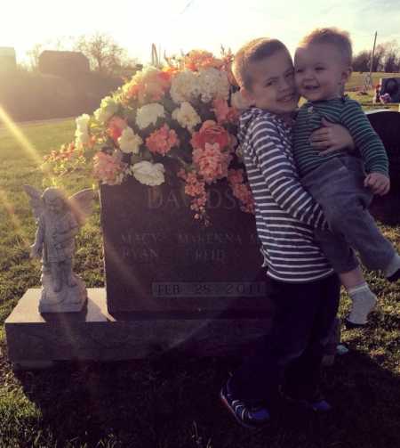 Two brothers smile for a photo next to their stillborn siblings' graves