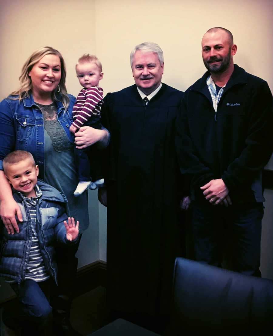 Family take a photo with a judge after adopting their son