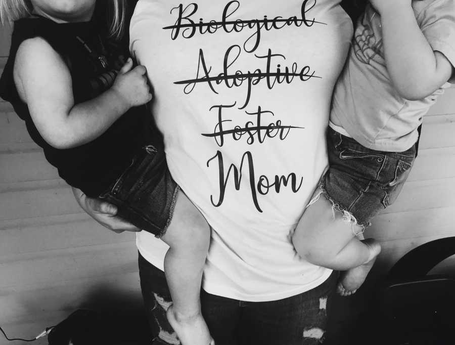 Mom holds her kids while wearing a shirt with "biological adoptive foster mom"