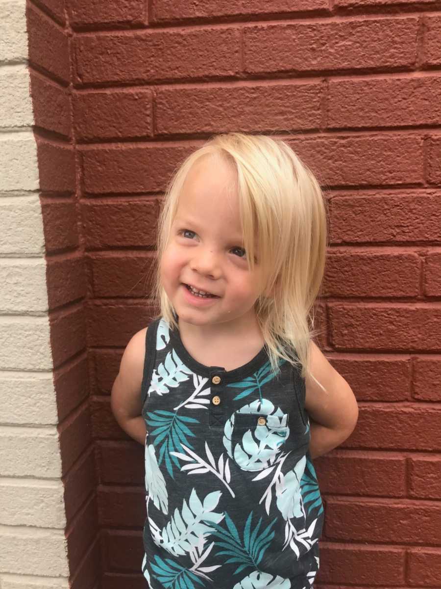 Mom takes a photo of one of her kids in leaf-patterned tanktop