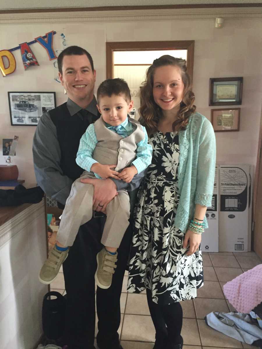 Young couple stand with their adopted son at a birthday party