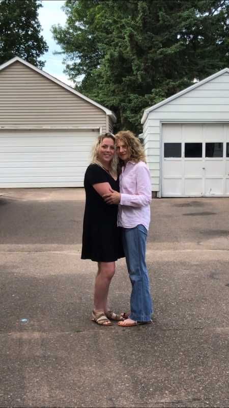 Sisters take photo together while hugging with garages behind them