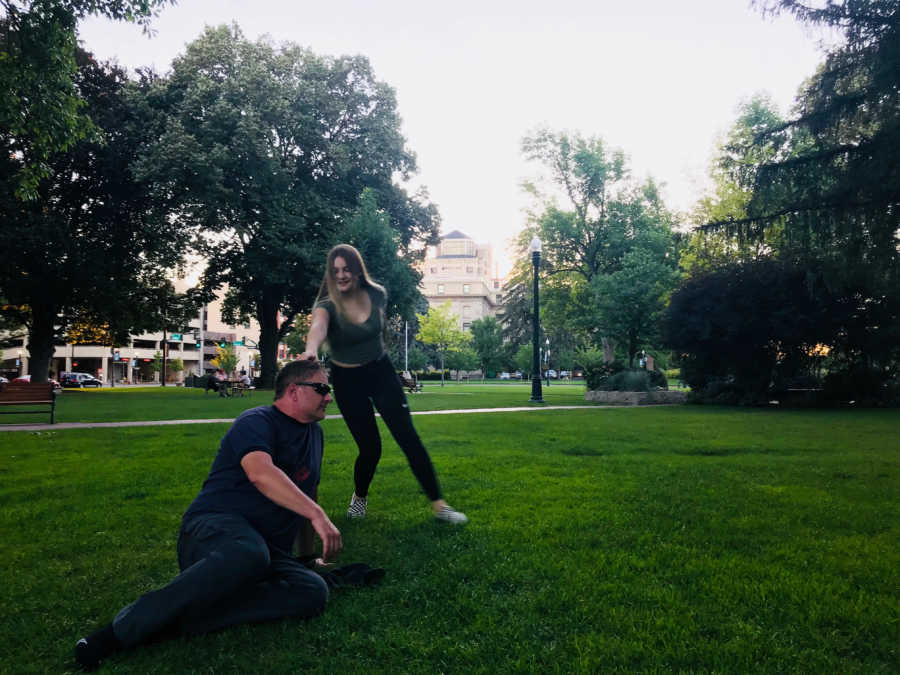 Mom snaps candid photo of daughter and father playing around in a park together