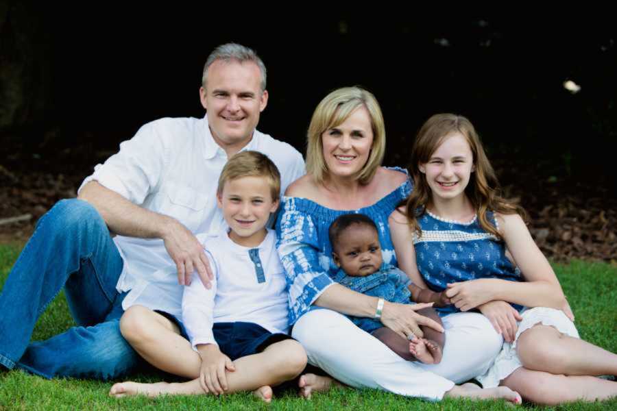 Foster family pose on grass with biological children and foster child