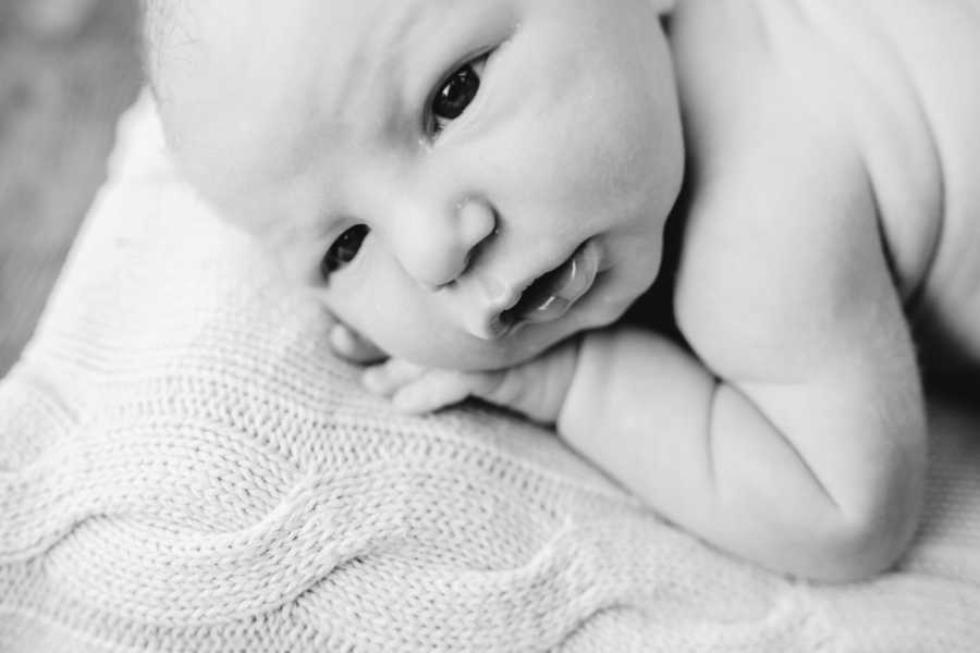 Newborn baby lays on crocheted blanket during tummy time