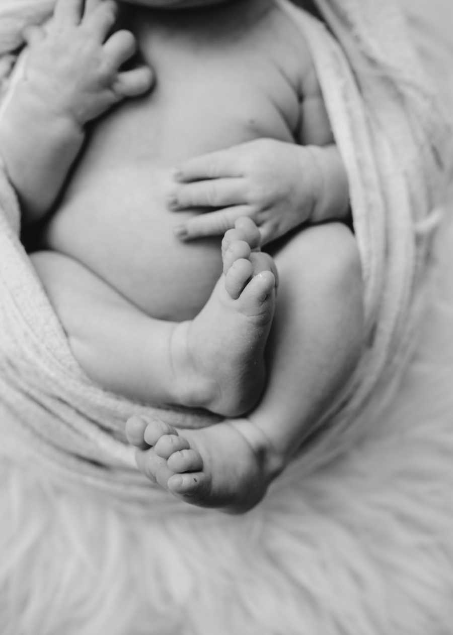 Newborn photographer takes up-close photo of newborn swaddled in a blanket