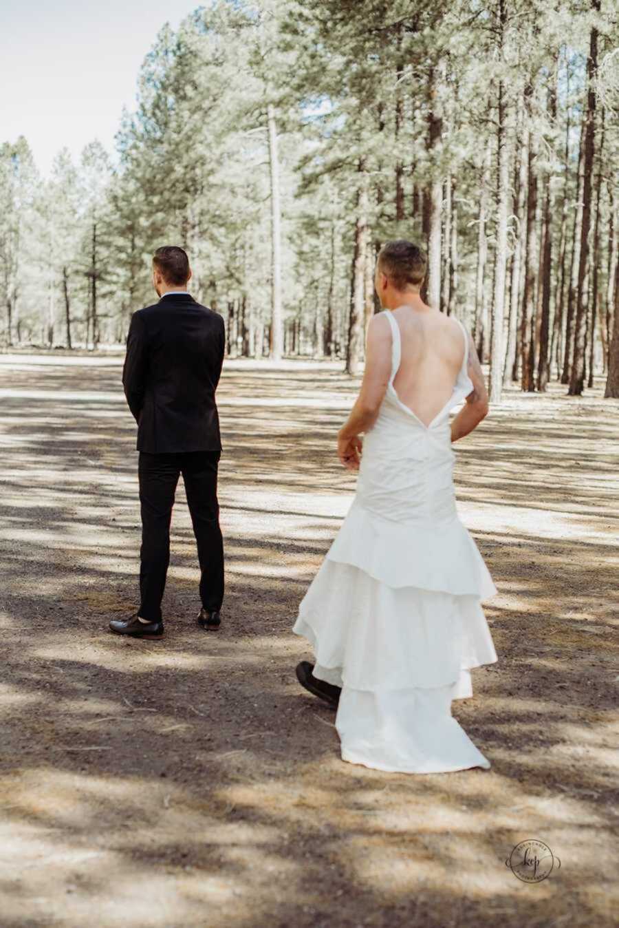 Man in wedding dress standing behind groom