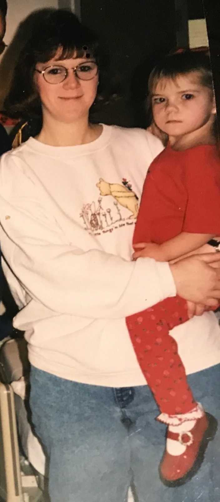 Little girl born with heart defect looks serious while mom wears a Winnie the Pooh sweatshirt