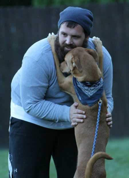 Man who was an alcoholic holds onto dog whose paws are on his shoulders