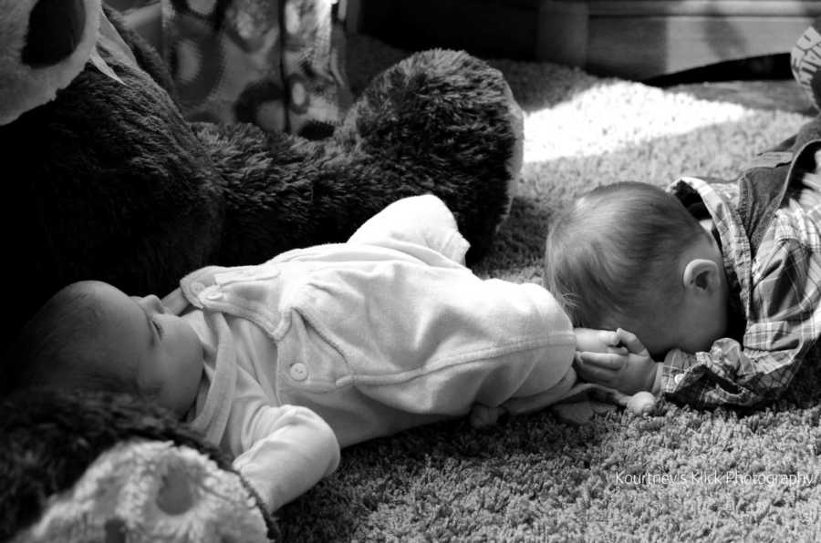 Infant with Chromosome 7 inversion laying on floor touching newborn sisters foot