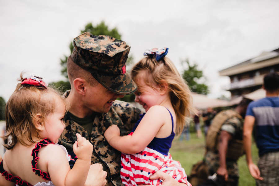Little girls smile in arms of soldier father who just returned home