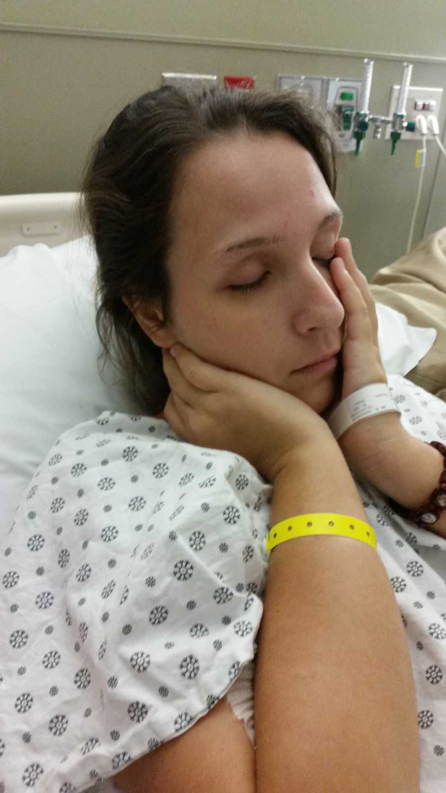 Young woman who overdosed lying in ICU holding her hands to her face