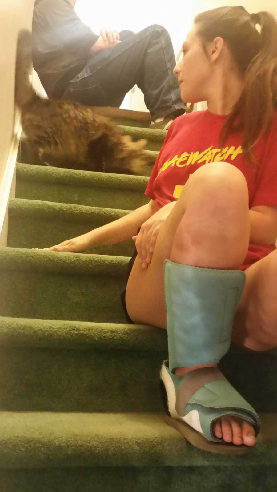 25 year old who overdosed sitting on steps of home with braces on her legs looking back at cat behind her