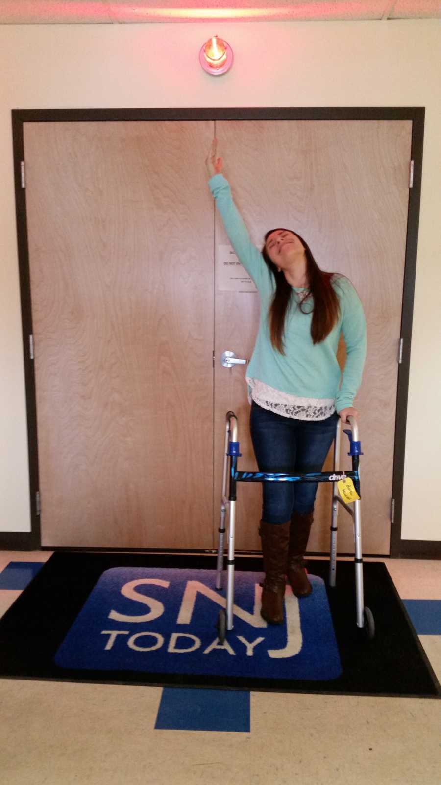 Young woman who overdosed stands with walker on doormat that says, "SNJ Today"