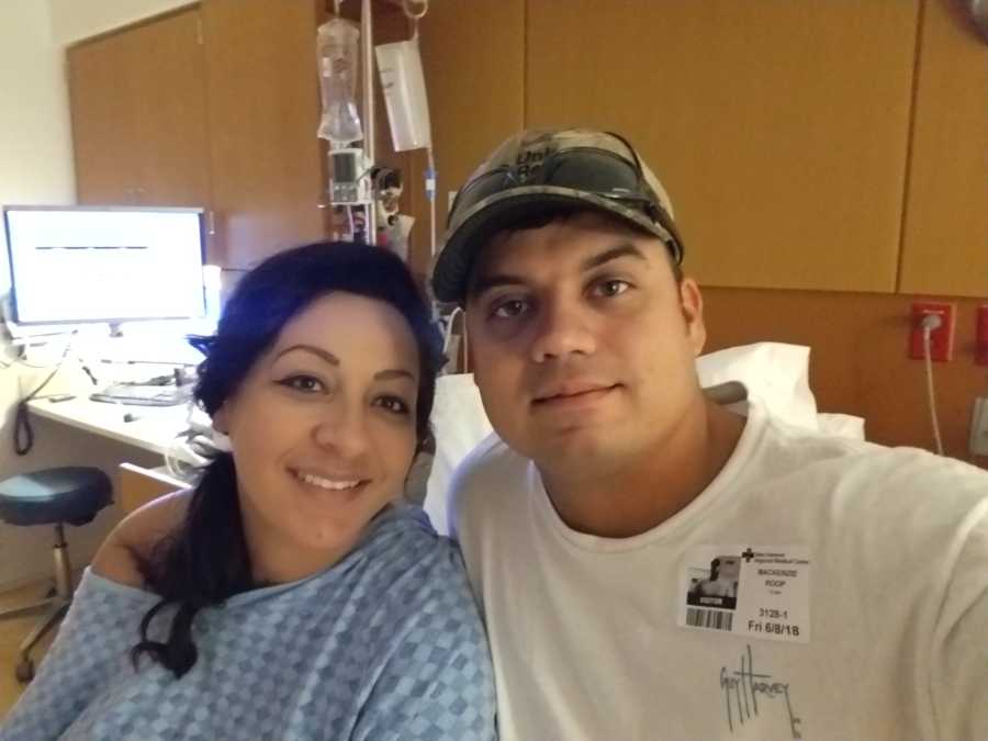 Husband and wife who struggles to get pregnant with third child smile in hospital room