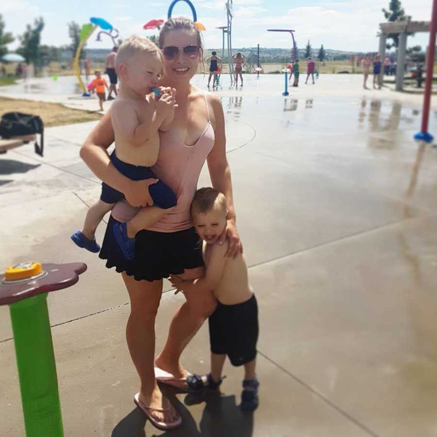 Mother whose children gave her a panic attack stands at water park holding one son with other at her side