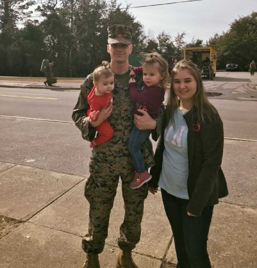 Soldier husband holds both daughter beside his wife before he leave for deployment