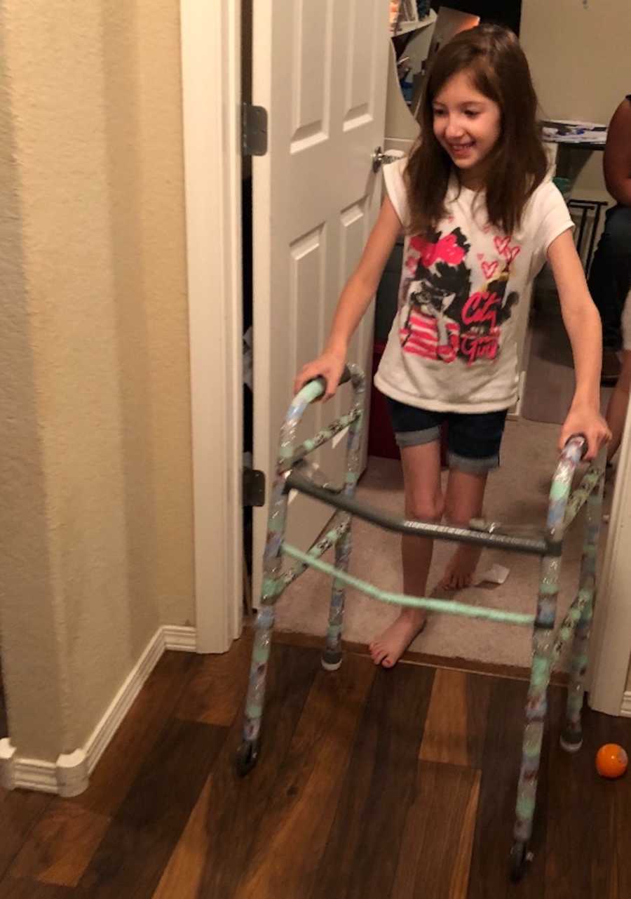 Little girl smiles while practicing walking with a walker