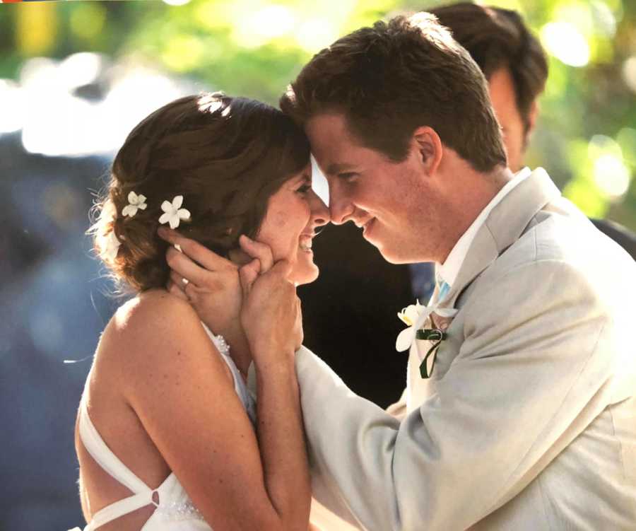 Bride and groom who struggle with relationship with their in-laws are smiling with heads together 