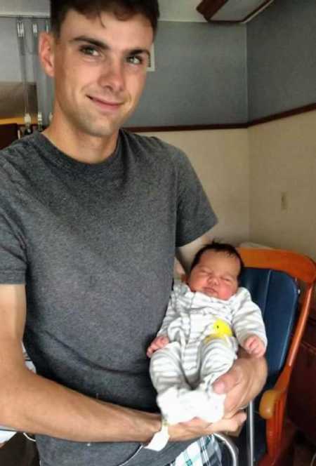 Soldier husband smiles holding his second child not long after her birth