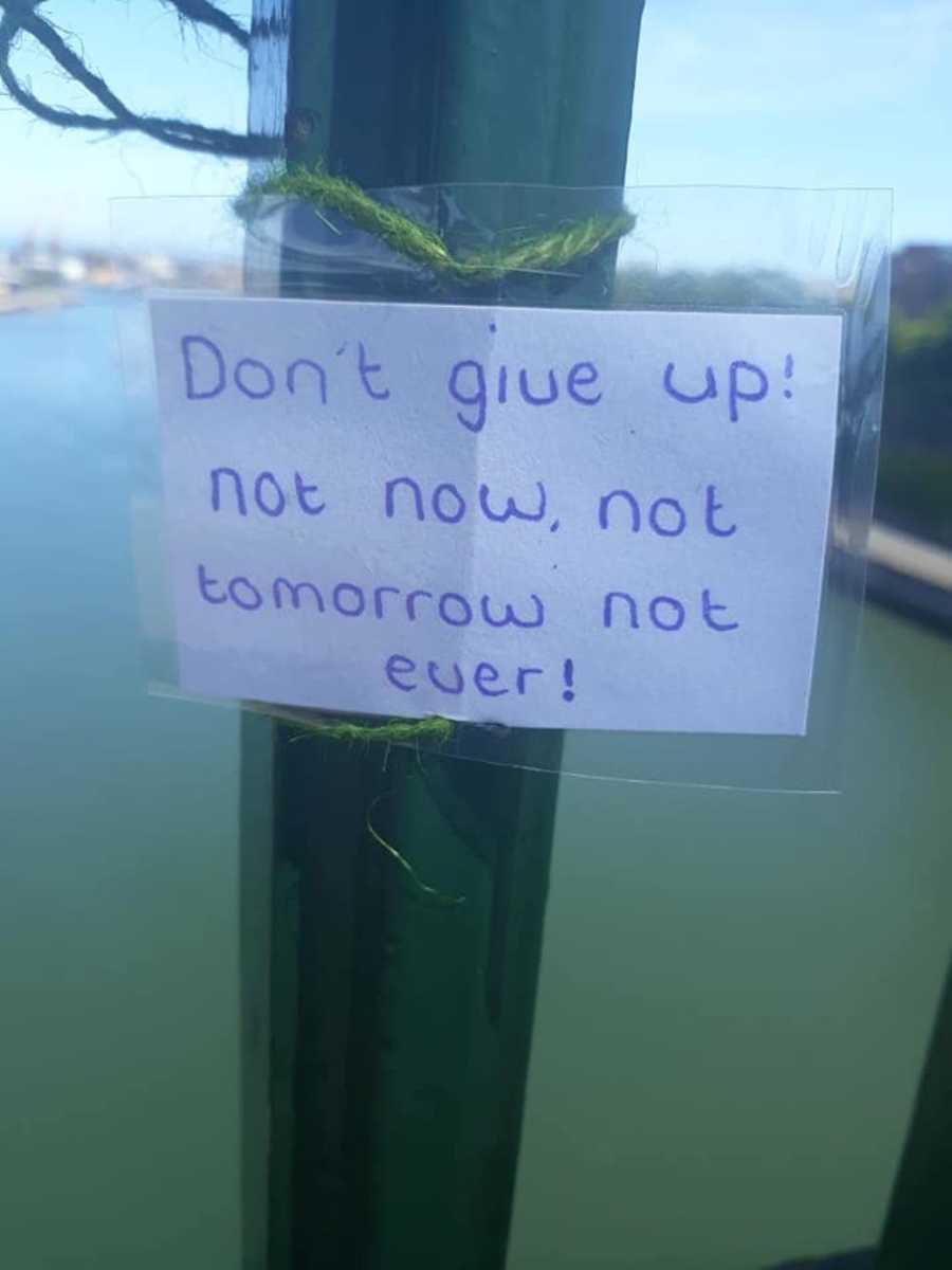 Woman snaps up-close photo of motivational card attached to a bridge