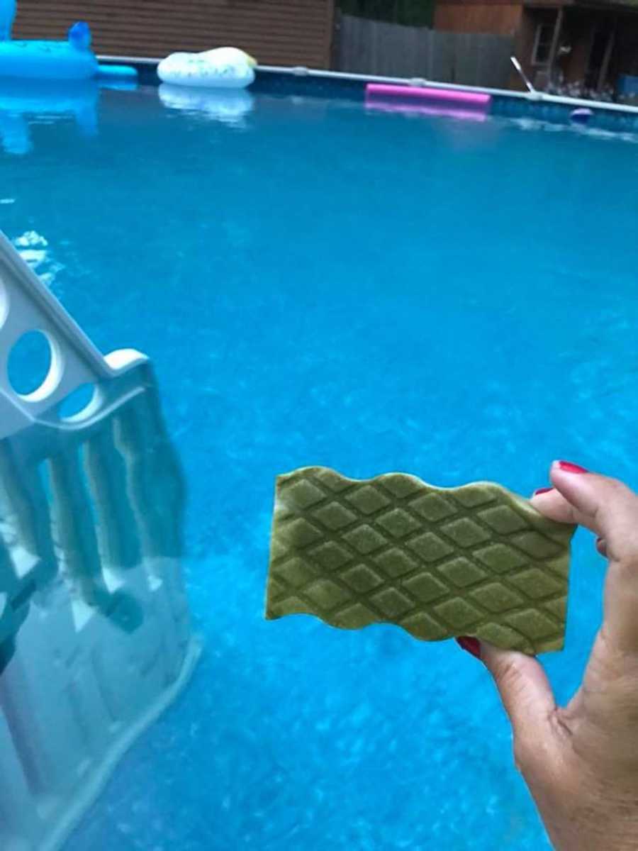 Woman holds up dirty Mr. Clean Magic Eraser with her clean pool behind it