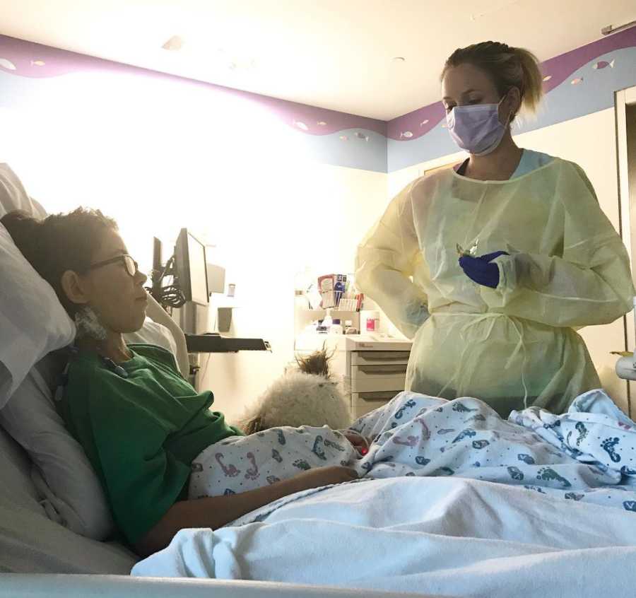 Nurse stands beside young boy in hospital bed who is recovering from having a pace maker put in him