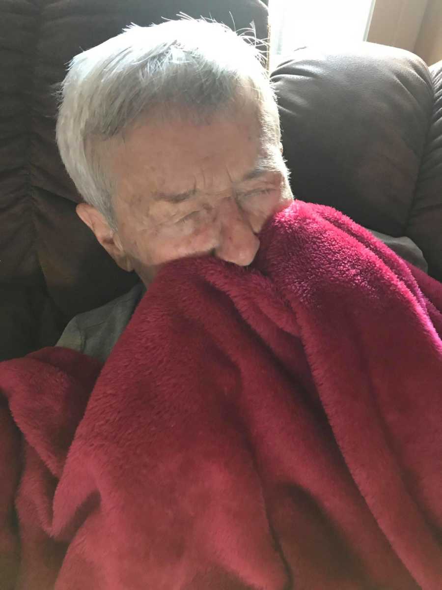 Woman battling dementia cuddles up on the couch under a red blanket