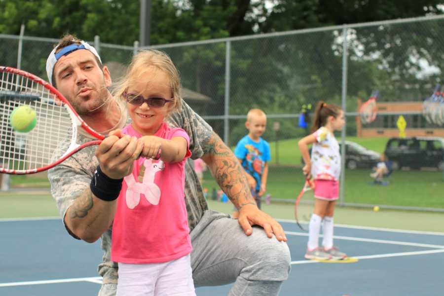 Recovered alcoholic teaching little girl how to play tennis
