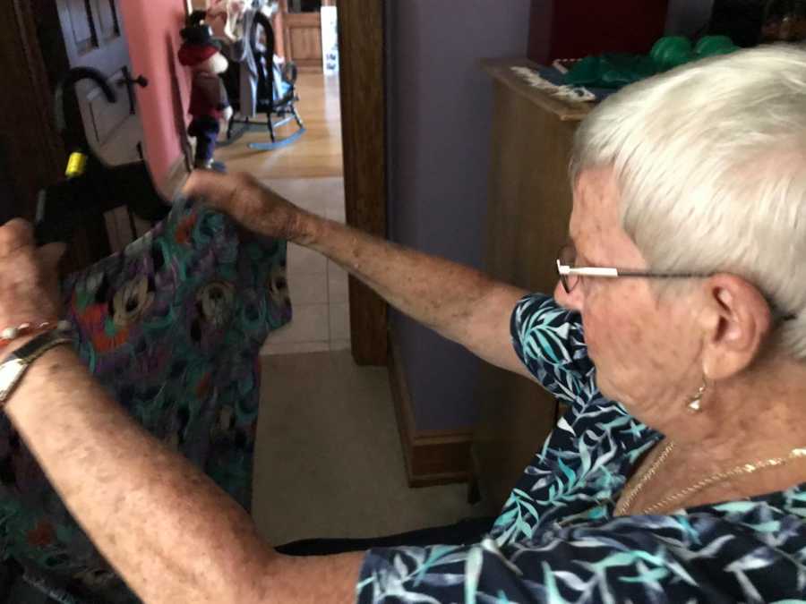 Woman with dementia holding up a nurses top with mickey mouse all over it