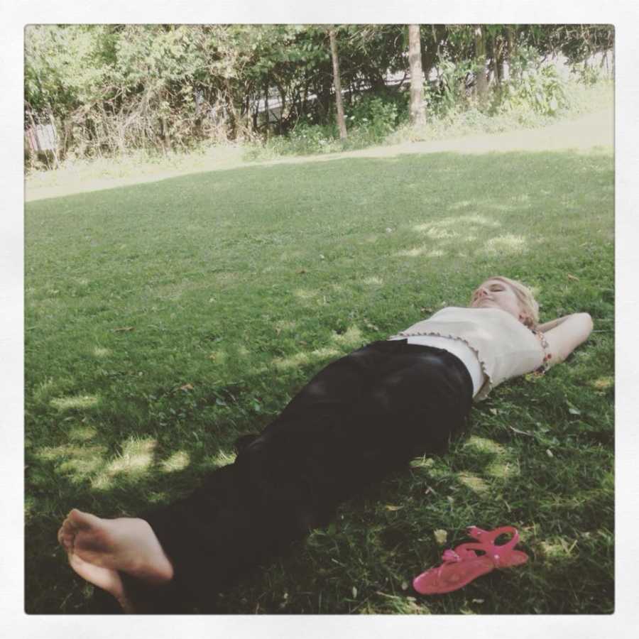 Woman lays in the grass while enjoying some time outside in the sun