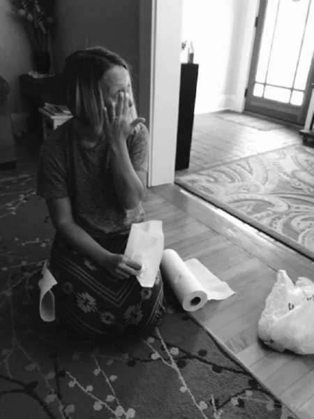 Mom of three sits on the floor and cries next to a paper towel roll