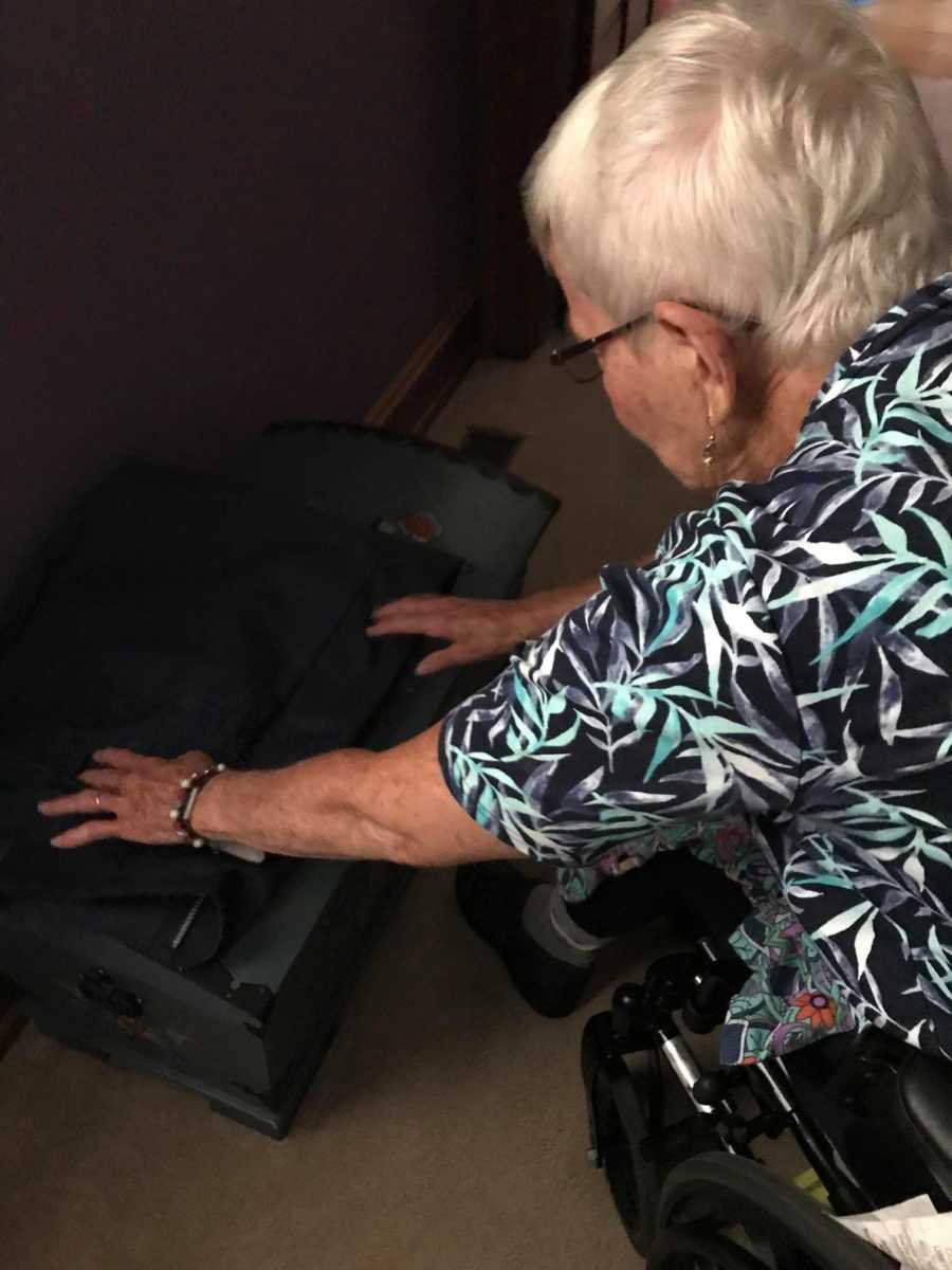Woman in wheelchair with dementia leaning over adjusting something on floor
