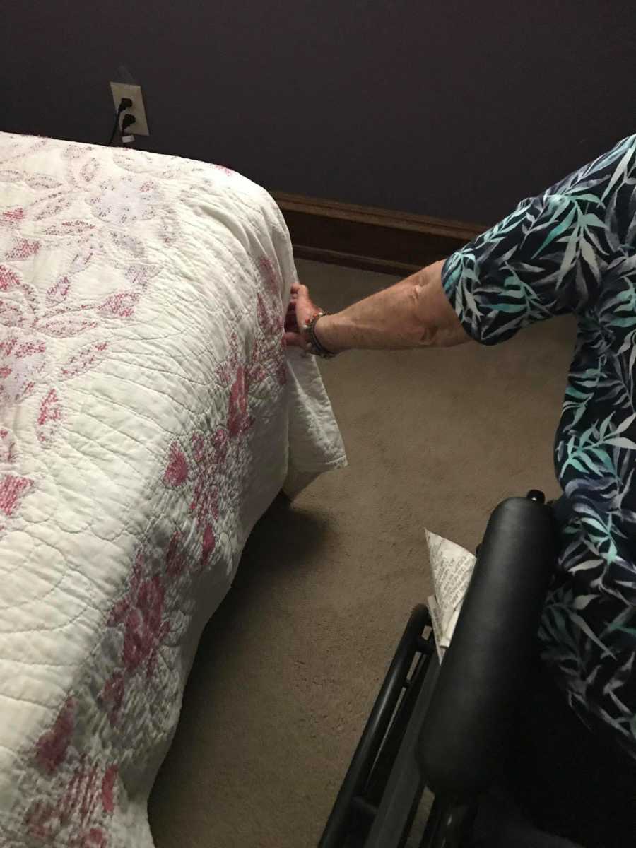 Woman with dementia sits in wheel chair adjusting corner of bed to the way she likes it