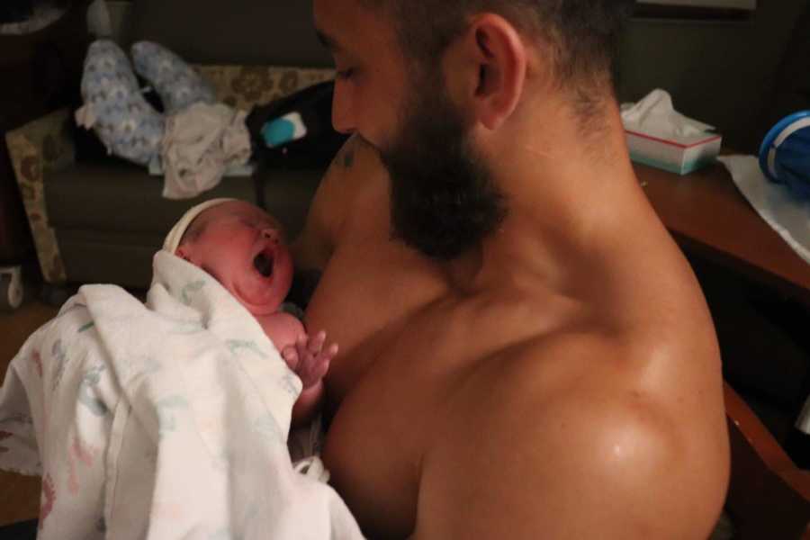 Dad holds newborn child while shirtless for skin to skin contact