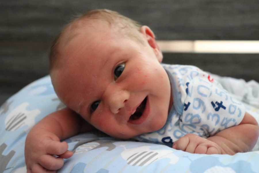 Baby smiles at the camera while attempting to hold his head up