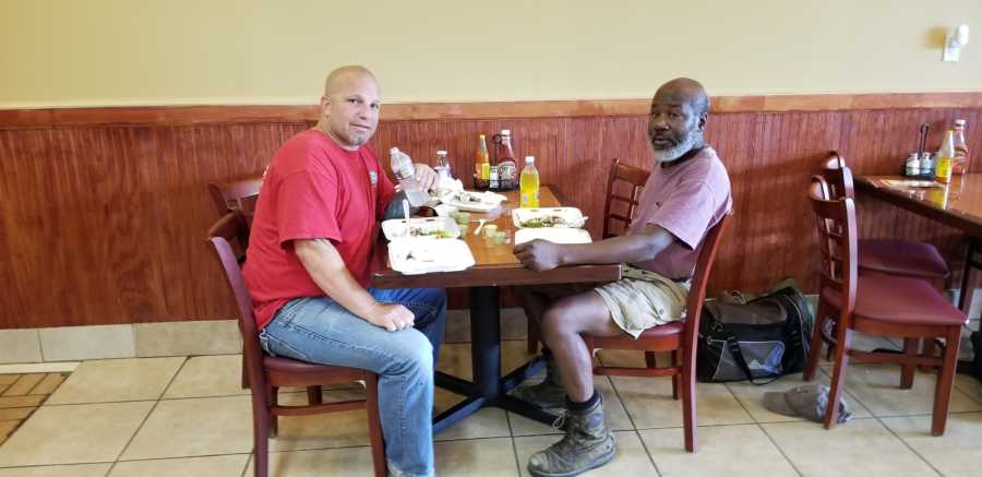 Man sits at restaurant table with homeless man he helped out