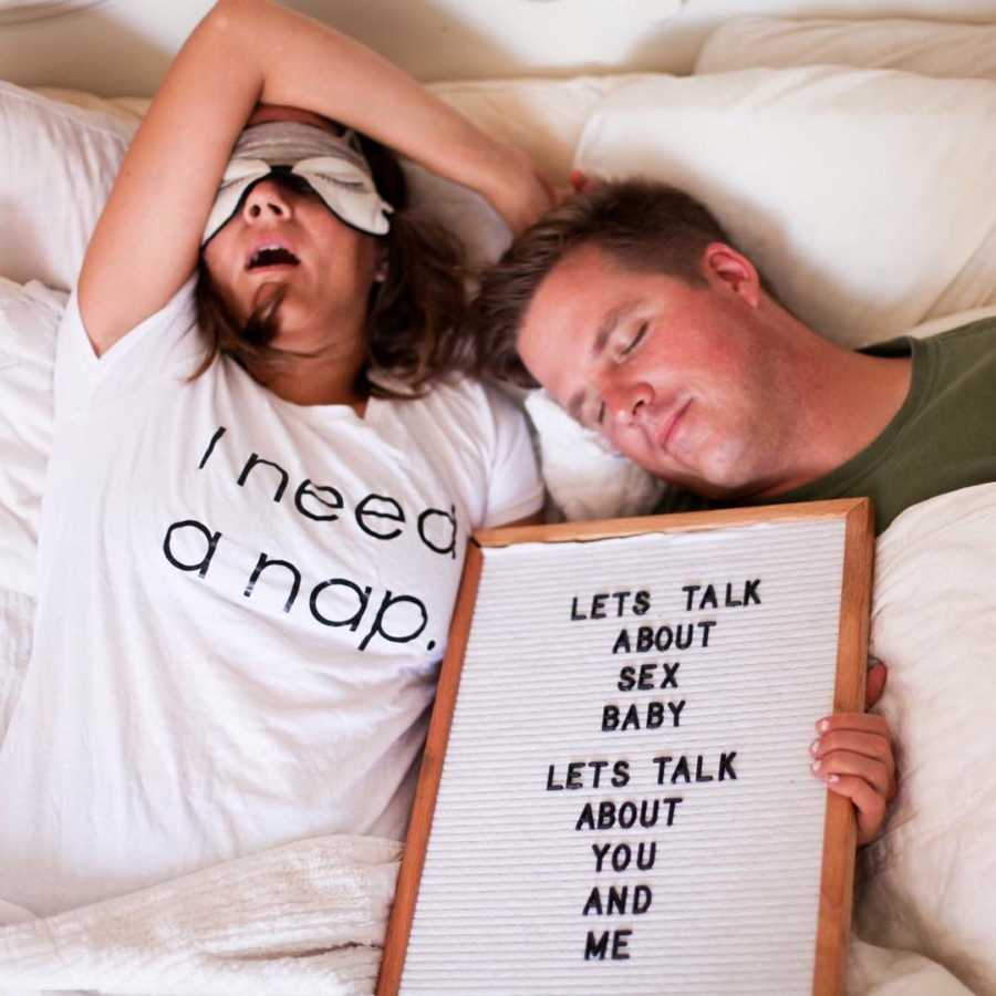 Mother and father with triplet babies lie in bed asleep with sign saying, "let's talk about sex baby"