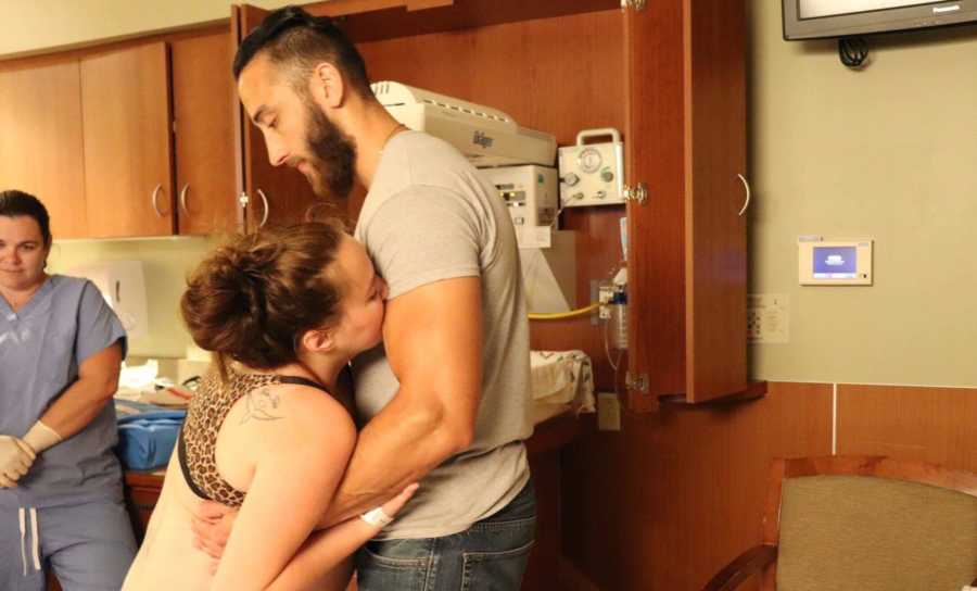 Husband holds his pregnant wife up while she experiences contractions during labor